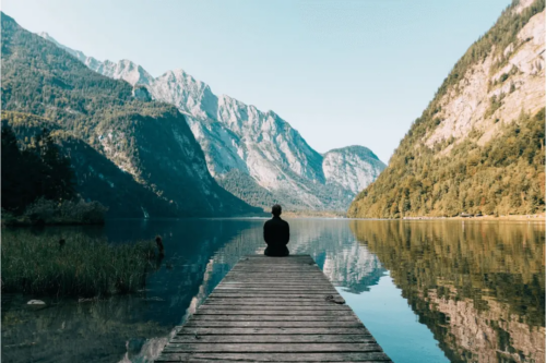 Young person sits practicing mindfulness in nature