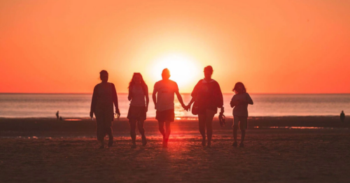 A family walking on the beach during sunset