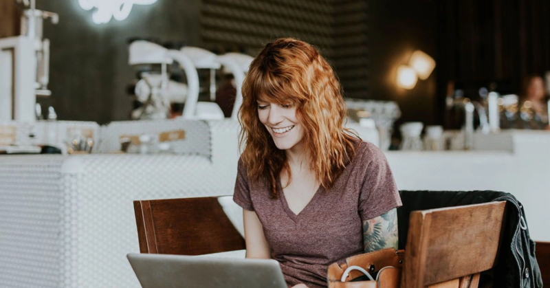 young adult woman sitting in a coffee shop searching for therapy online