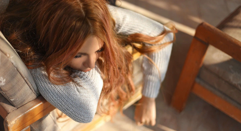 Teen laying on the arm of a chair looking sad