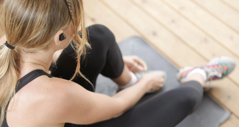 Teen girl sitting down tying her shoes to go workout for self care.