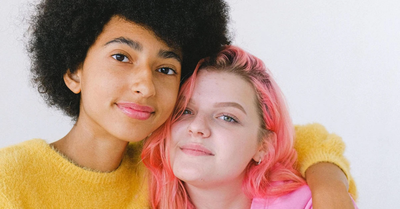 Two non-binary teens hug
