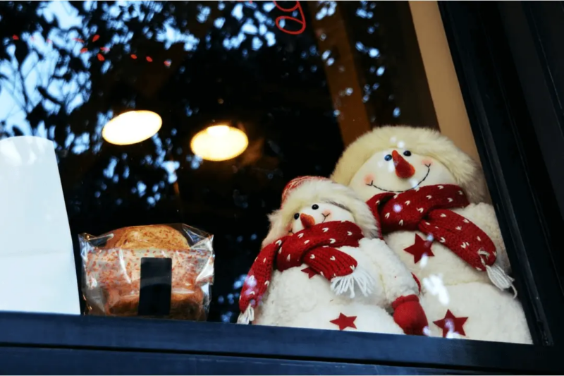 Two stuffed decorative snowmen displayed in a window for the winter holidays