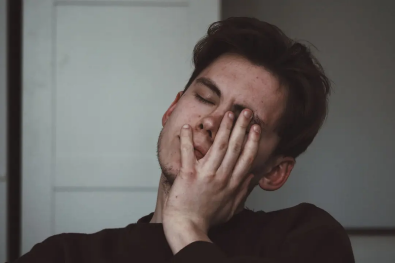 A male teen sits with his head in his hand