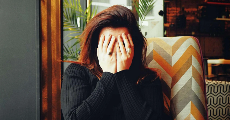 A woman experiencing chronic pain covering her face with hands