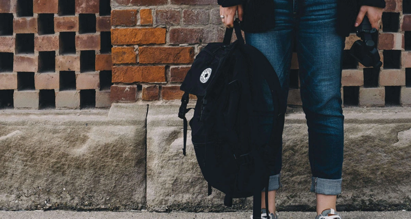 Person with backpack coming out of a school