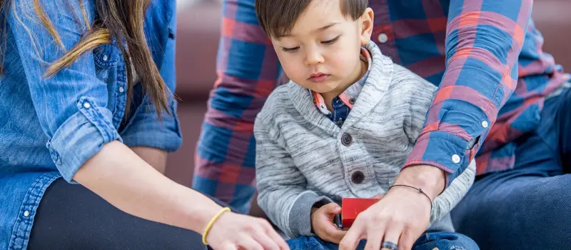 Young child playing with Legos with their parents