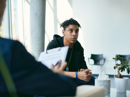 Teen sitting on a couch talking to a therapist