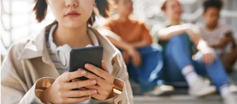 Young female on her phone with friends behind her