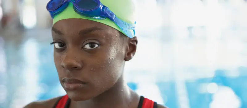 Young female with a swim cap and goggles on at the pool