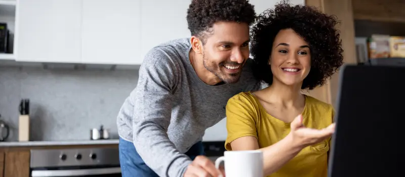 Someone coping with BPD shows their favorite person something on their computer, smiling next to them.