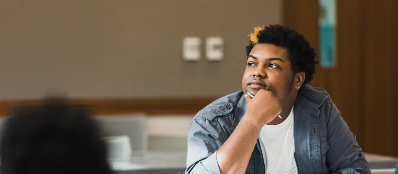 A Gen Z indiviudal sits thoughtfully in class.