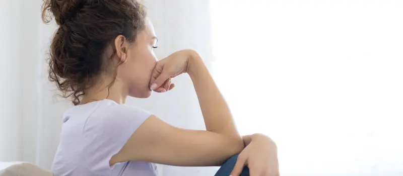 Teen looking out a window with her hand on her face