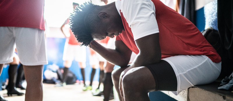 Athlete sitting at locker dealing with depression