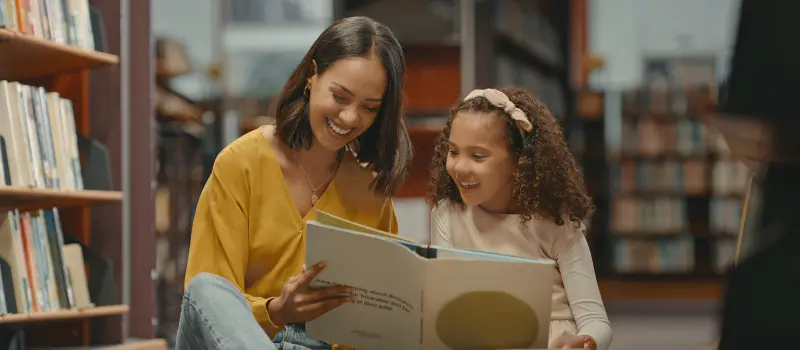 Mother reading a story to her daughter in a library