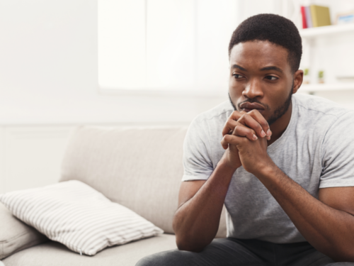 Young adult man struggling with depression clasping his hands