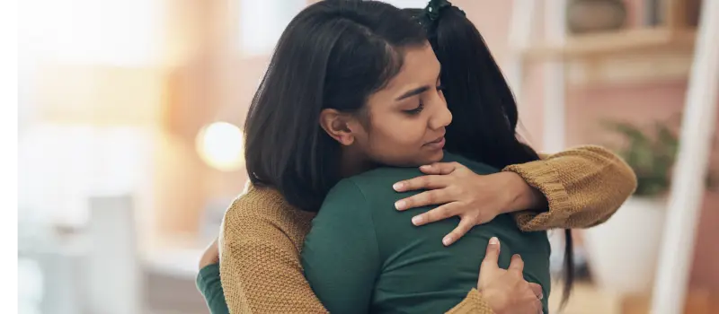 Teenage girl comforting her friend with a hug