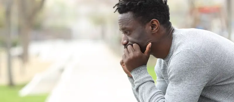 Man sitting in a park thinking about the trauma he has gone through