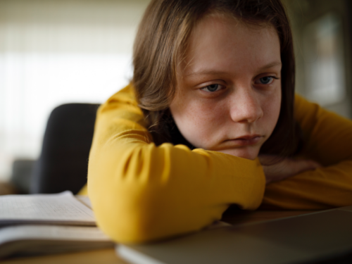 Girl with ADHD looking frustrated over her school work