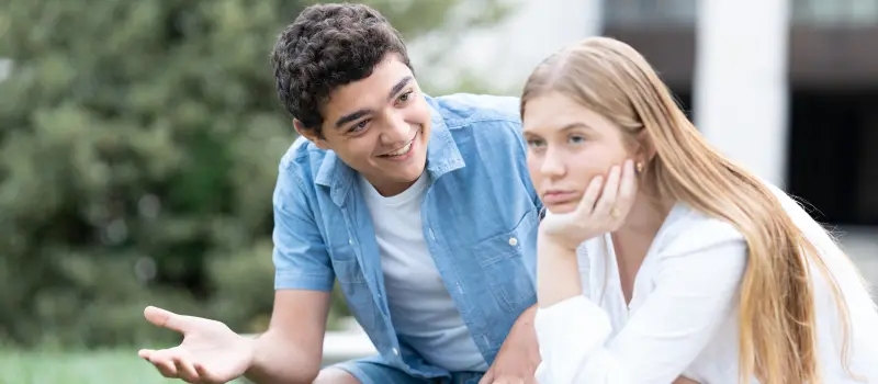 Teen boy trying to talk to his girlfriend while she spaces out