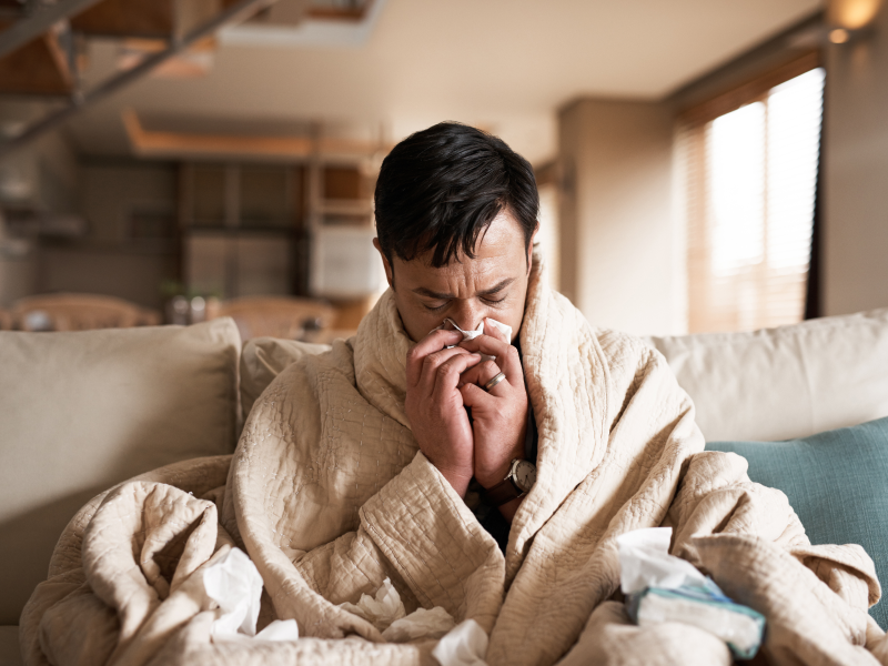 Man sitting on his couch blowing his nose