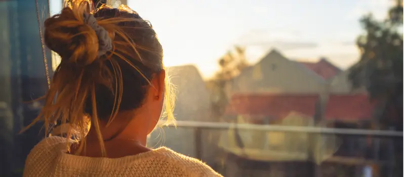 A teen girl struggling with being parentified stares of her window 