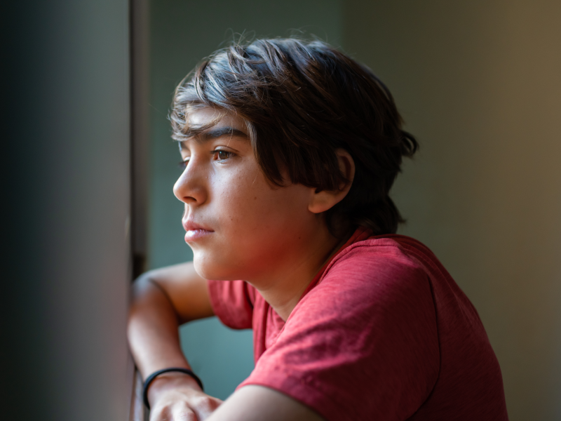 A young teen boy looks off camera as he deals with a traumatizing household