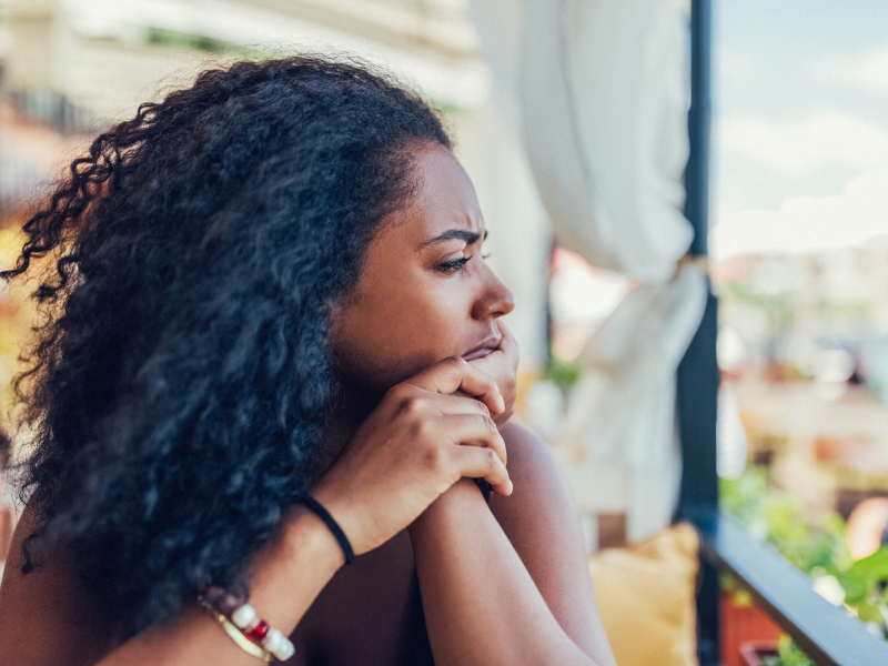 A young adult woman with PTSD and agoraphobia sits at home alone