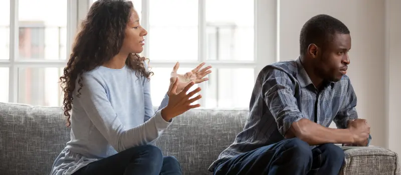 Couple on a couch arguing with the one person turned away