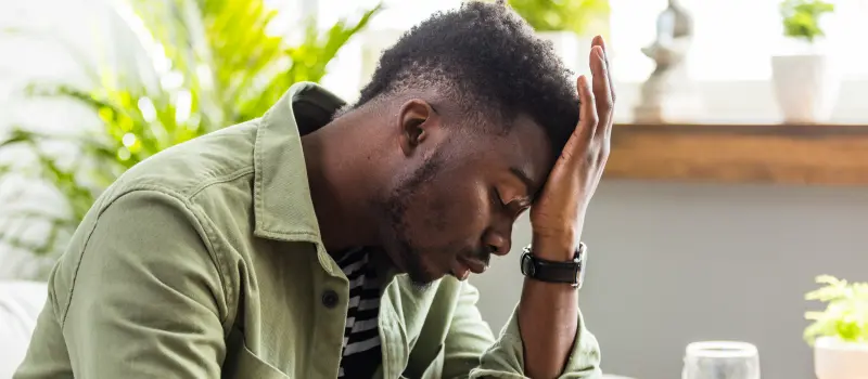 Male sitting with his hand on his head not feeling well