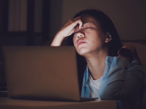 A young person stares at a computer screen in upset as they deal with the symptoms of emotional damage from past trauma.