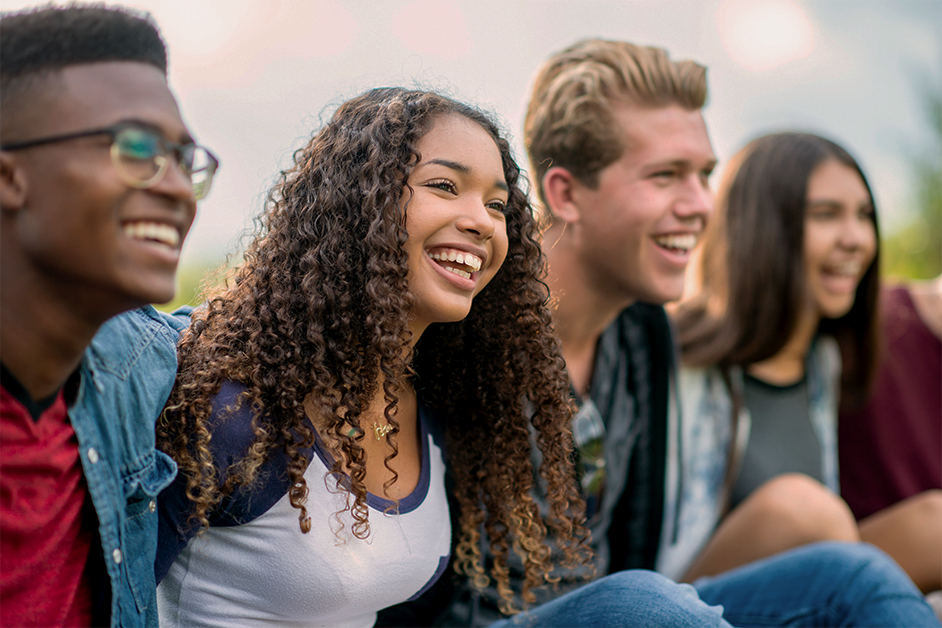 Young adults with their arms around each other laughing