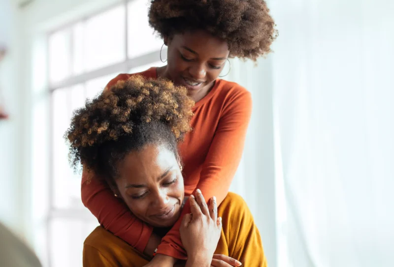 Child in orange shirt hugging mom