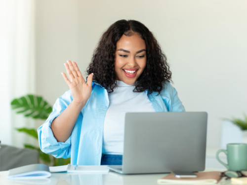 A group therapy participant smiles at a computer screen as she joins a trauma-informed group therapy session.