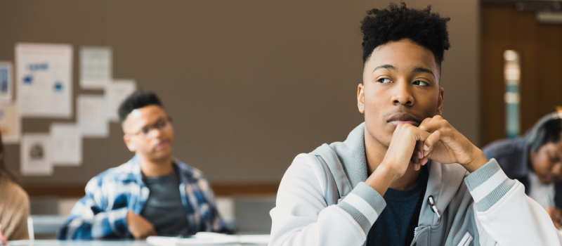 A young man sits in school distracted by his emotional trauma