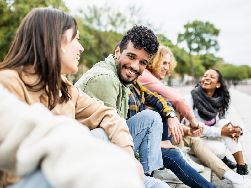 A person in a green shirt sitting in a row of friends smiles at the camera after learning skills to become more resilient.