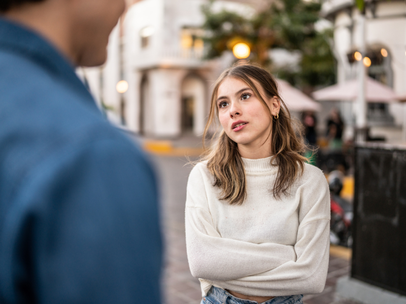 A person dealing with reactive abuse in her relationship crosses her arms as she looks at her partner.