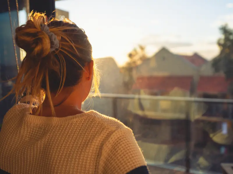 A young woman going through exposure therapy stares out of her window during sunset