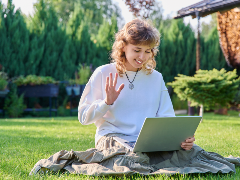 A young woman meets with her drama therapy group on her laptop