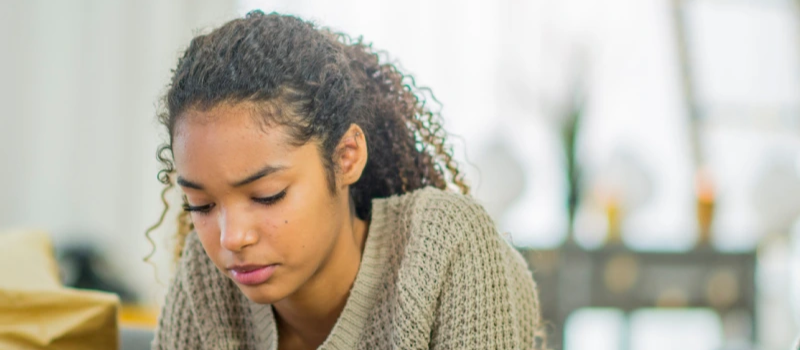 Teen girl with curly hair looks down at her phone