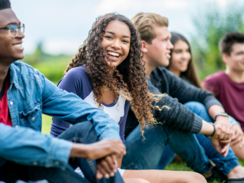 A young person who has successfully completed IOP and made strides in her mental health looks at the camera smiling.