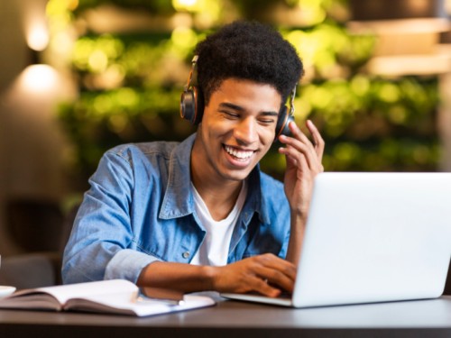 Someone wearing headphones smiles while looking at their computer screen during an intensive outpatient program.