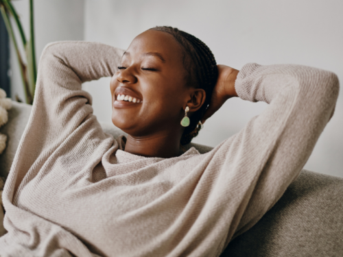 A clinician reclines and smiles after practicing self-care. After investing in her own well-being, she is better able to support clients.