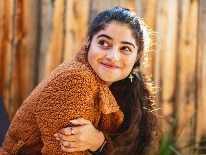 A person in an orange jacket smiles after learning the tools to address her anxiety disorder.