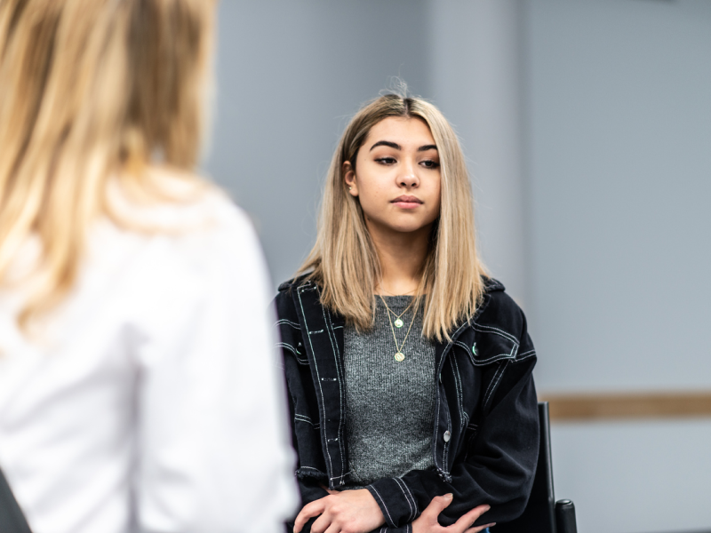 A young person with blonde hair sits in a therapy session and receives treatment for intermittent explosive disorder.