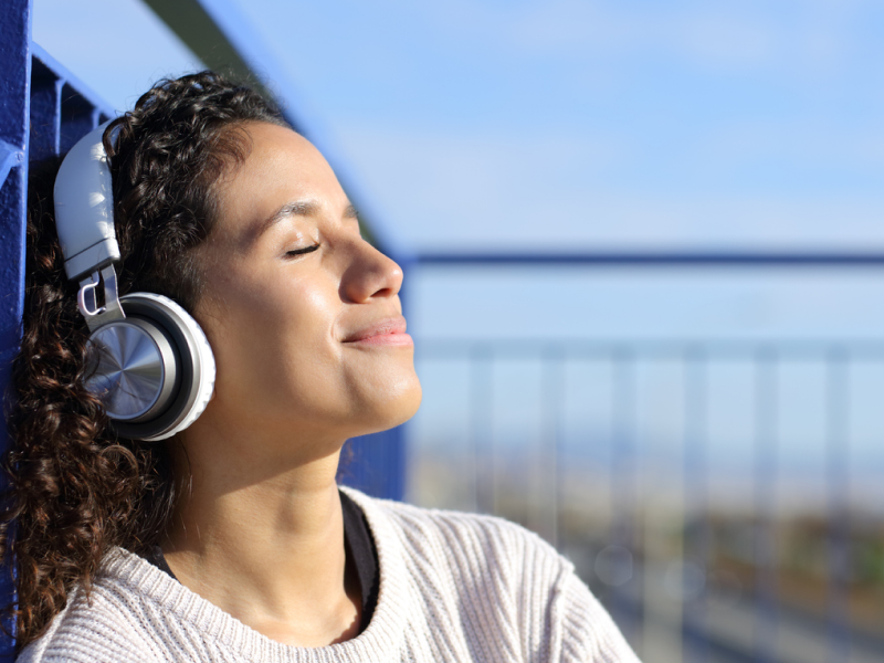 A person in headphones closes her eyes and smiles after successfully using a guided meditation to help manage a panic attack.