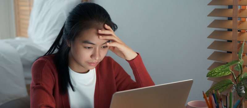 A person in a red sweater dealing with grief and loss attends a grief group session on her laptop.