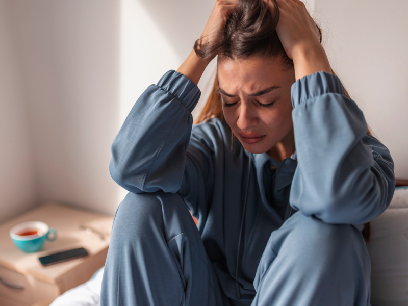 A person in a blue sweatsuit grabs her hair as she deals with a silent anxiety attack.