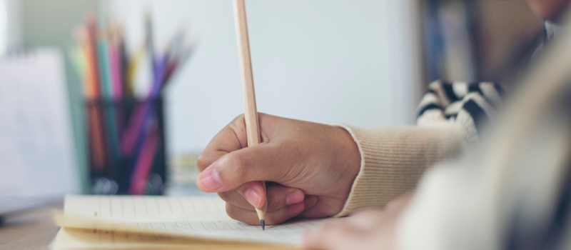 A person struggling with anxiety holds a pencil and journals as a way to better manage her anxiety symptoms.