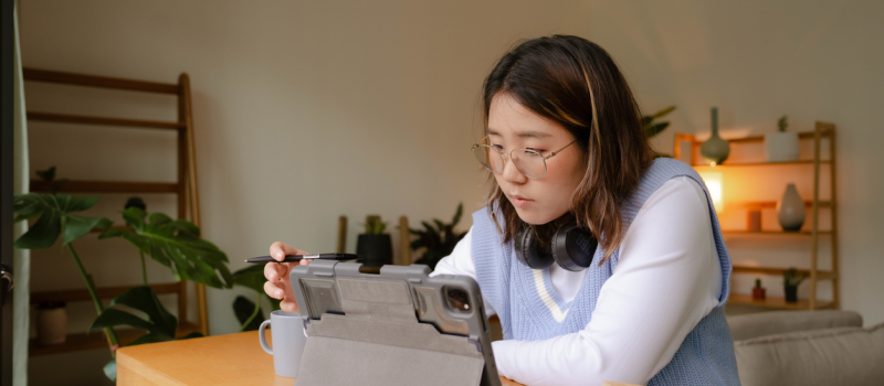 A high school student wearing a blue sweater vest focuses on a mental health activity on a tech device.